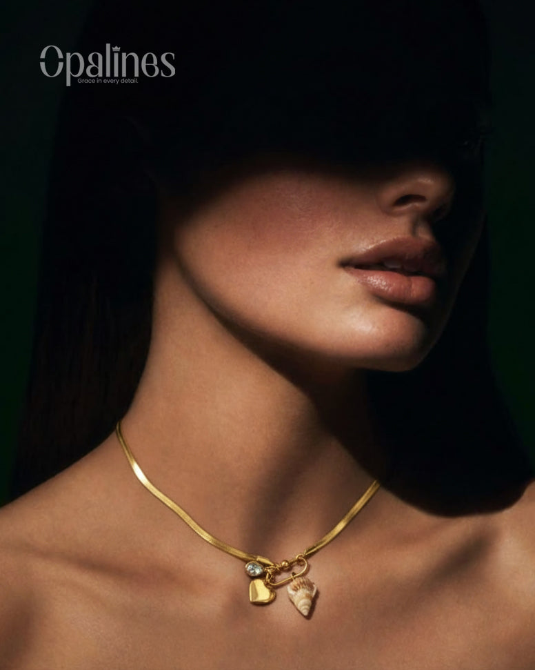 stunning gold necklace from Opalines features a heart-shaped locket, a diamond accent, and a seashell charm