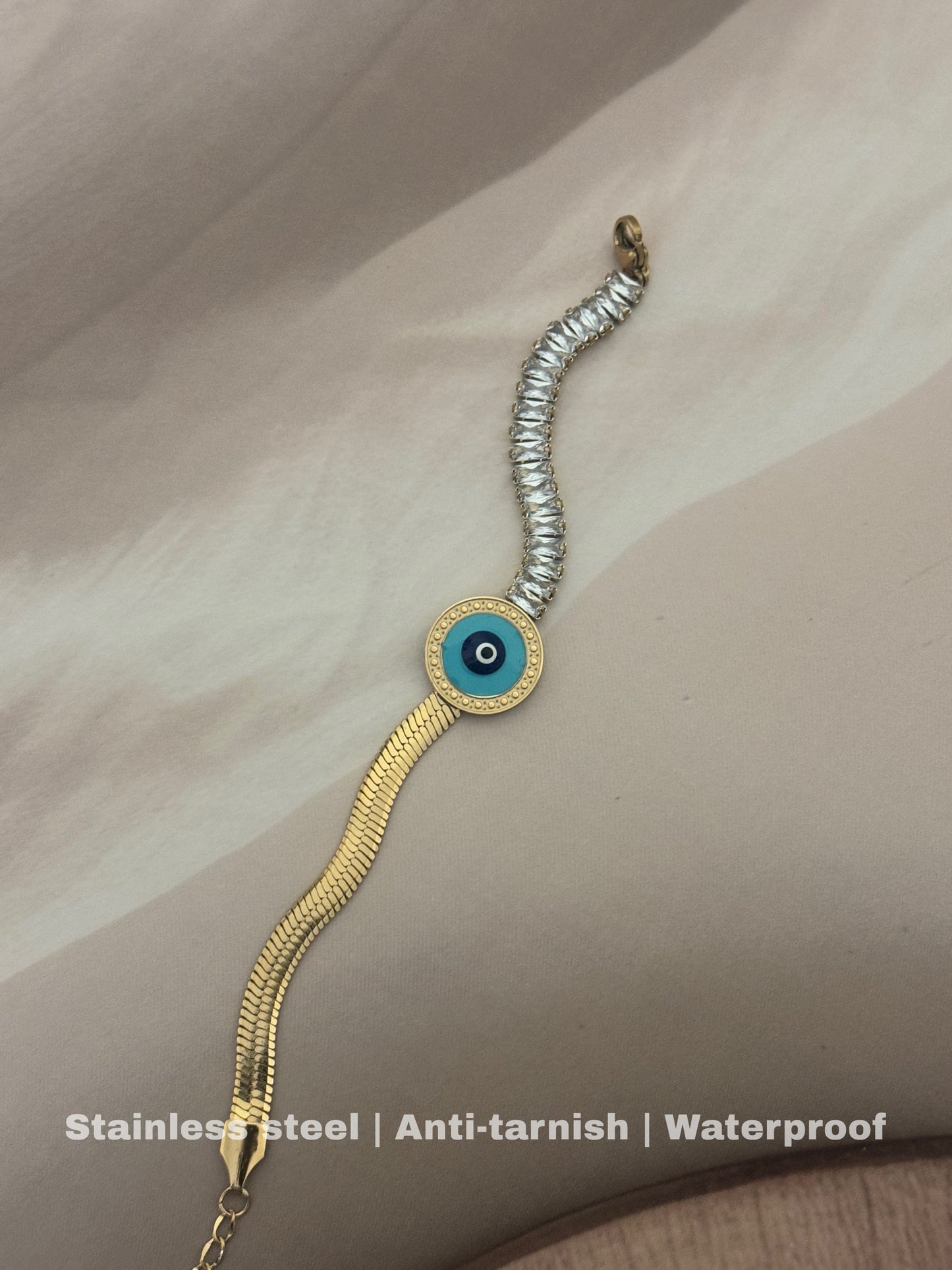 stainless steel bracelet features a bold gold chain with a mesmerizing blue & black evil eye charm